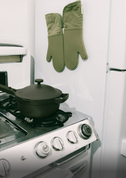 Green Hot Mitts hang above a stove, which has a black Mini Perfect Pot on it