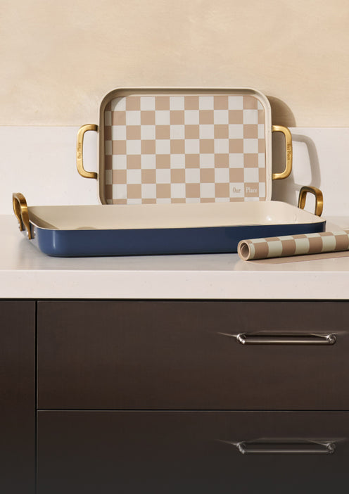 Set of trays with checkered lid and gold handles on a kitchen counter.