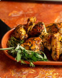 Bowl of roasted chicken with herbs on a rustic wooden surface