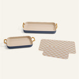 Two rectangular ceramic trays with gold accents and a checkered cloth on a white background