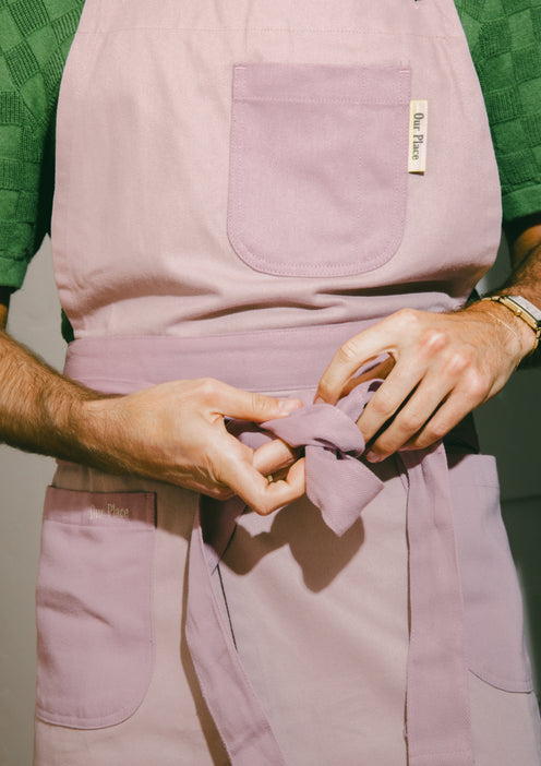 A chef ties a purple Home Cook Apron around the body