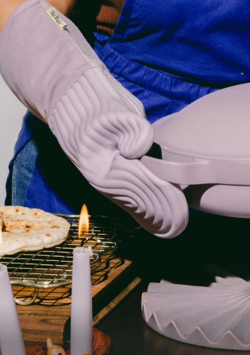 A chef uses purple Hot Mitts to carry a purple Always Pan