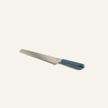 A bread knife with a serrated stainless steel blade and a dark teal handle, set against a plain off-white background.