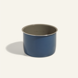 A blue, cylindrical metal container with a silver rim is shown against a plain, light background. The container casts a soft shadow to the left.