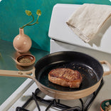 beige cast iron always pan seating a steak on a stovetop