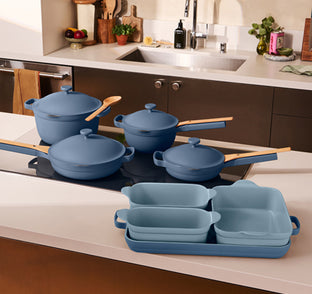 Set of blue cookware on a kitchen counter with a stove in the background