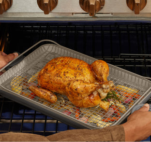 Roasted chicken on a baking tray being taken out of an oven.