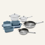 A Titanium Pro Cookware + Bakeware Set 2.0 featuring a collection of two lidded stainless steel pots, two frying pans, and blue ceramic bakeware.
