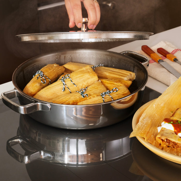Lifting the snug-fitting lid off a Titanium Braiser Pro filled with tamales.