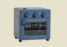A compact blue countertop oven with three control knobs on top, a clear front door, and a visible metal rotisserie inside, set against a plain beige background.