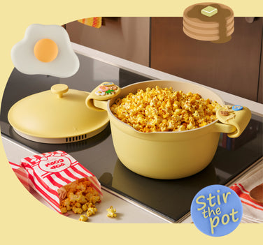 Yellow pot with popcorn on a stove, surrounded by a fried egg, pop corn box, and pancakes.