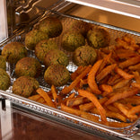 Fried falafel balls and sweet potato fries in a deep fryer basket.