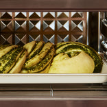 Baked bread with green pesto swirls in an oven.