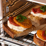 Bruschetta with tomatoes and basil being baked in an oven.