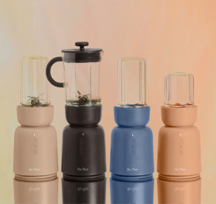 Four portable blenders in different colors on a reflective surface with a gradient background.