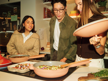 Three people cooking together in a kitchen with pots and pans.