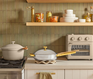 Kitchen scene with pots, pans, and an oven against a tiled wall.