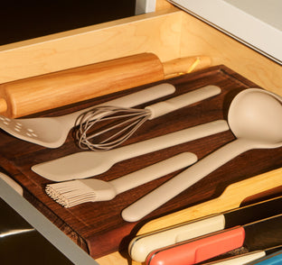 Set of kitchen utensils including a rolling pin, spatulas, and spoons in a wooden drawer.